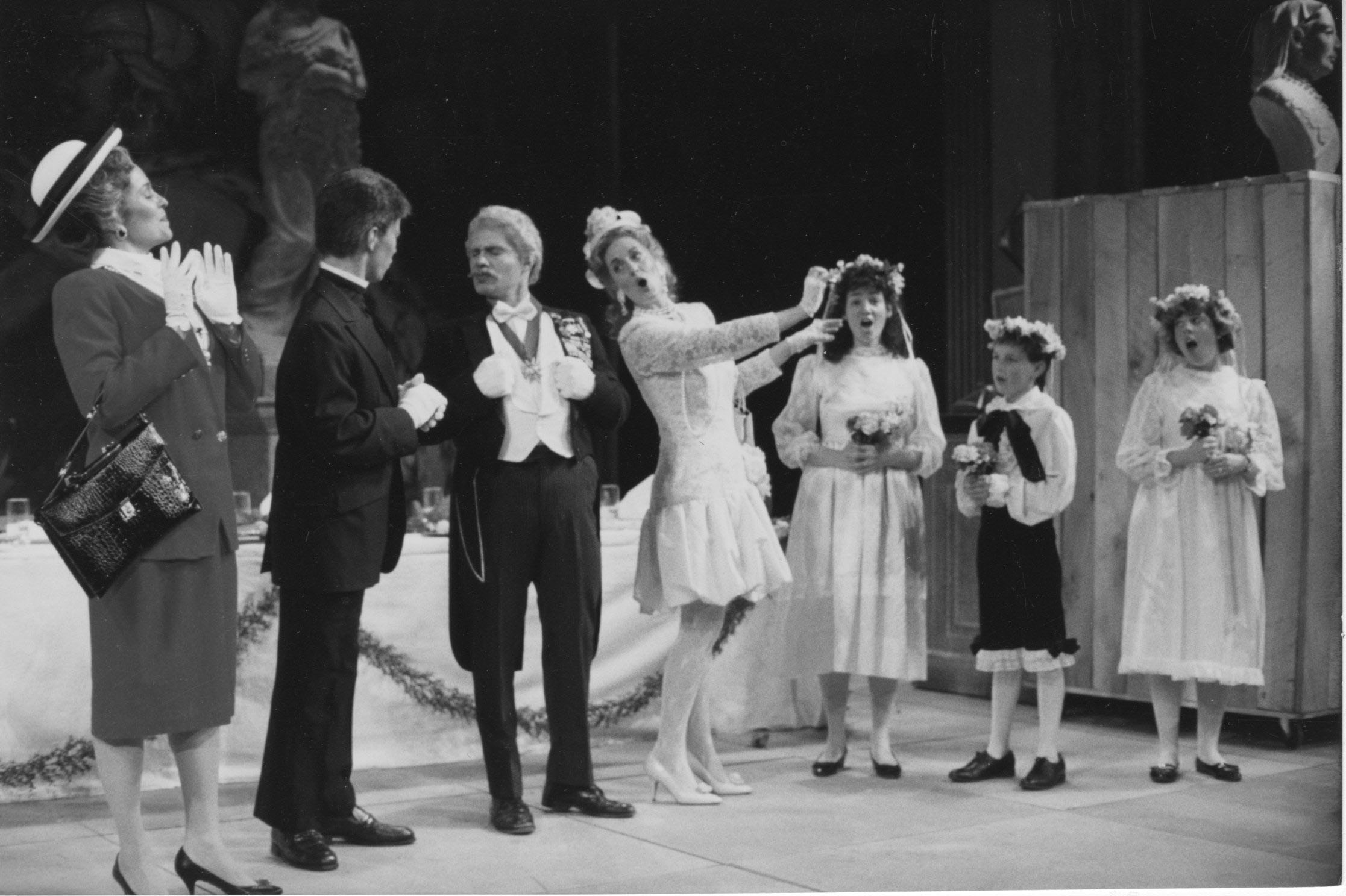 Lady Billows and others during the coronation scene, act II. Lady B’s likeness to Mrs. Thatcher—particularly with the handbag—is especially pronounced in this shot. Photo by Marcio Botelho. Richard Pearlman Collection.